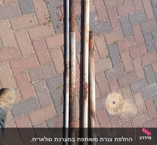 צינורות חלודים מונחים על רצפת אבנים משתלבות